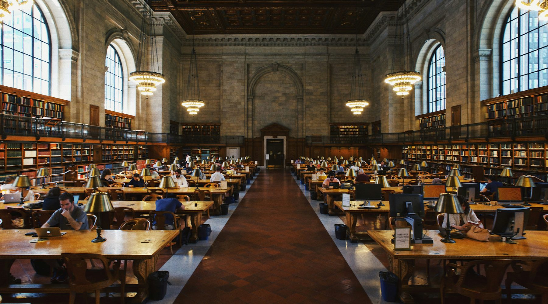 Students working at long desks in a university reading room